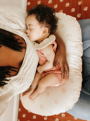 baby sleeping on a nursing pillow on mom's lap