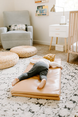 toddler laying on a toki mat play mat on the floor