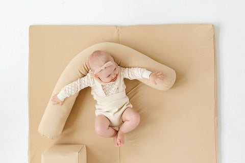 baby leaning against a toki mats support pillow and play mat
