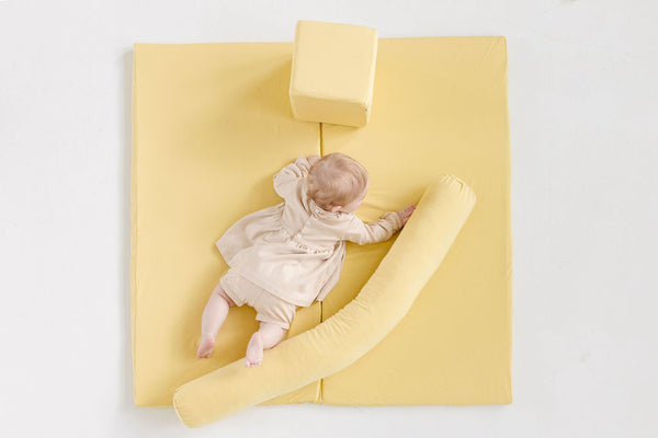 baby laying on a toki mats play mat in daisy yellow
