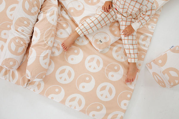 a child sitting on a toki mats play mat and support pillow with lena corwin's yin and yang print design