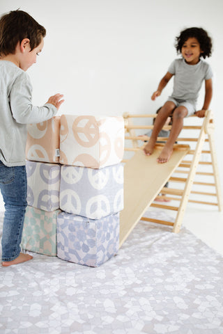 two kids playing with toki play cubes and a pikler triangle