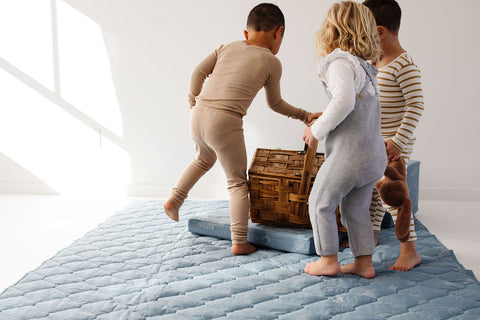 kids playing on a toki mats picnic blanket with a picnic basket