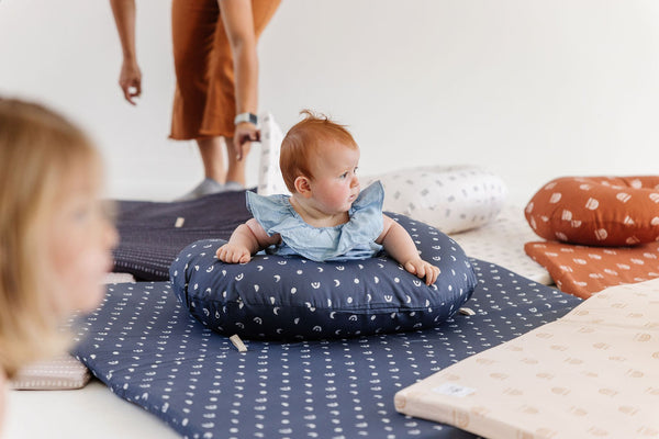 baby doing tummy time with a nursing pillow on a toki mats play mat