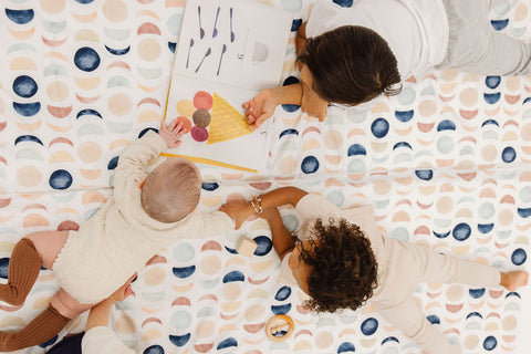 a baby and two toddlers playing on toki mats lunar phases mat