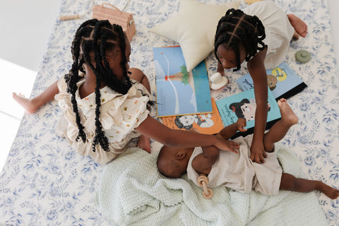 two girls playing on a blue florals and stripes toki mat