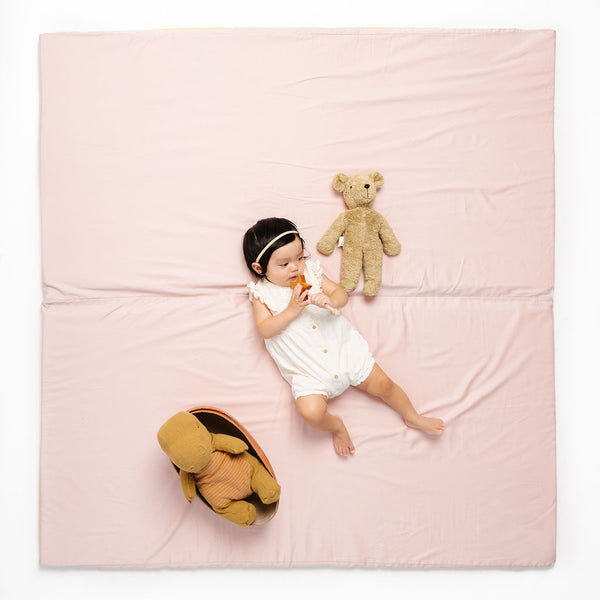 baby laying on a toki mats play mat in color tutu