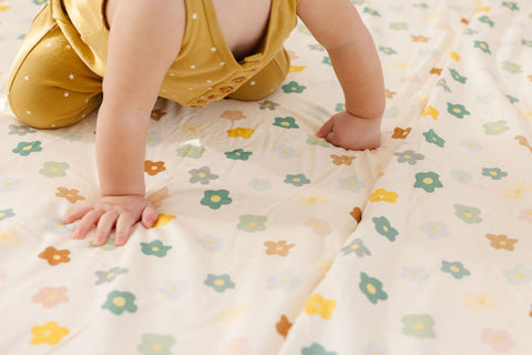 baby crawling on a playful posies play mat