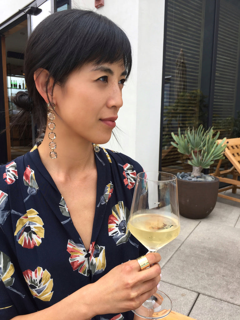 model holding white wine glass with janna Conner earrings at filifera rooftop bar hollywood