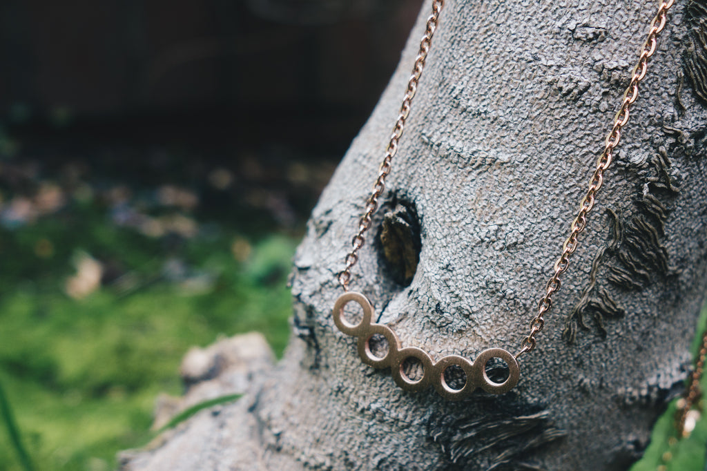 minimal circles necklace by janna Conner on tree branch in forest