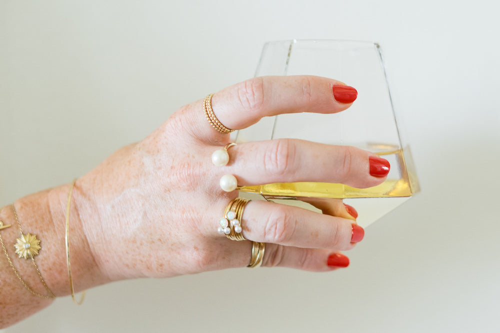 hand holding wine glass with red nails pearl rings by janna Conner