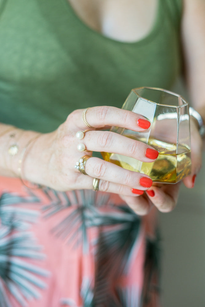 janna Conner holding white wine glass with red nails and pearl rings