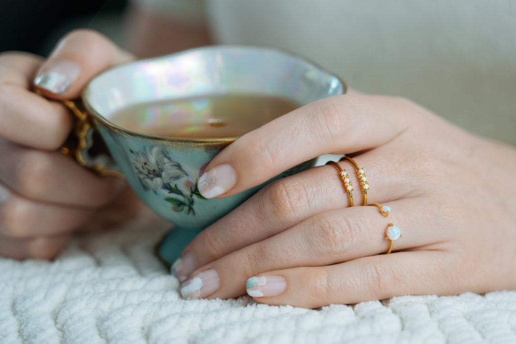 Janna Conner opal stacking rings on model hands holding vintage teacup