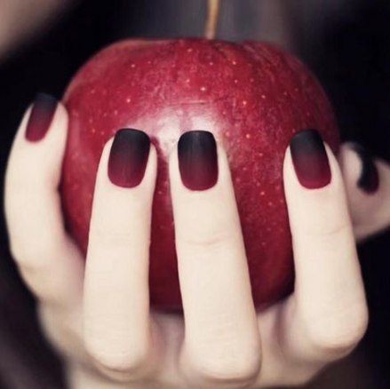 Ombre gradient red and black nails holding an apple