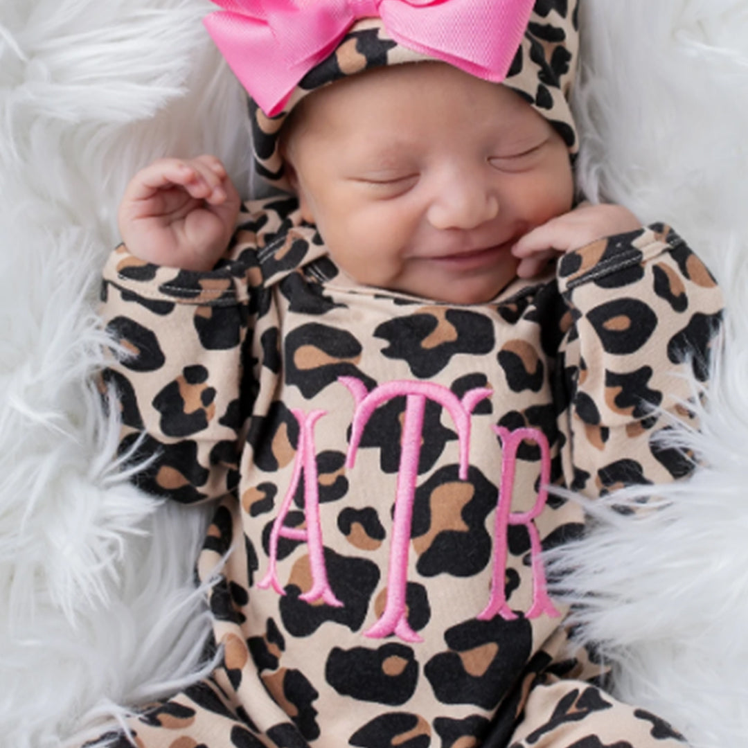 A happy, smiling baby wearing the Junie Grace Personalized Baby Girl Leopard Print Outfit.