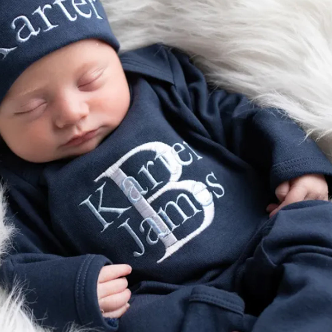  A baby boy wearing the super soft personalized Navy Blue Boys Hat & Romper outfit from Junie Grace.