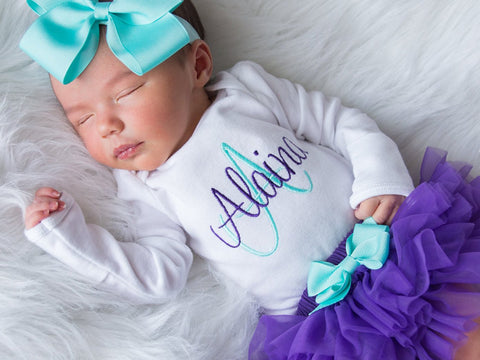 Sleeping baby in purple tutu, personalized top, and blue bow.