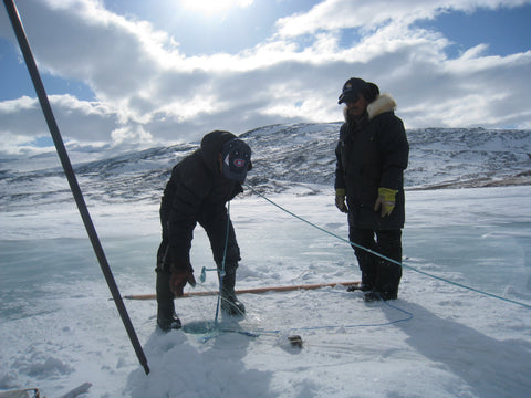 two Inuit fishermen pull nets from the ice