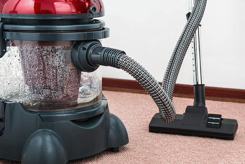 Red and black vacuum cleaner cleaning the carpet