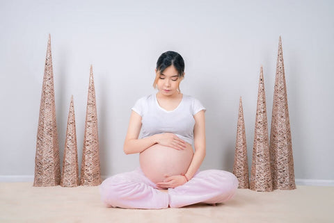 seated pregnant woman with hands on belly