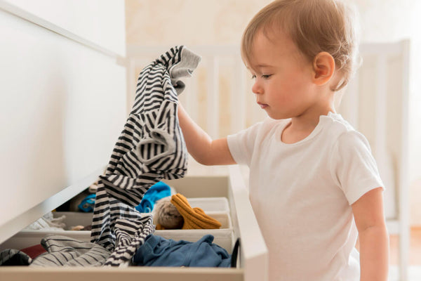 toddler rummages through the dresser with clothes