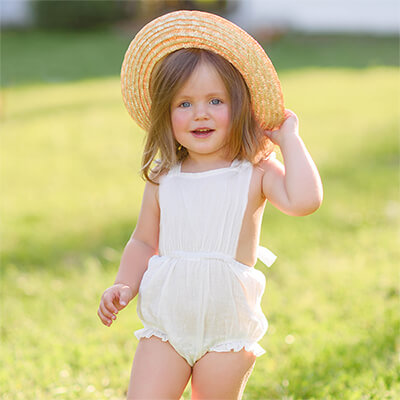 toddler girl in a white romper on the grass