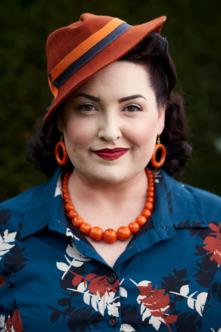 Splendette ヴィンテージにインスパイアされた 1940 年代 1950 年代スタイルの彫刻が施されたフェイクライト フォックス オレンジのジュエリーと、慢性的に過剰な服装をした The Glambassador Christine Cochran