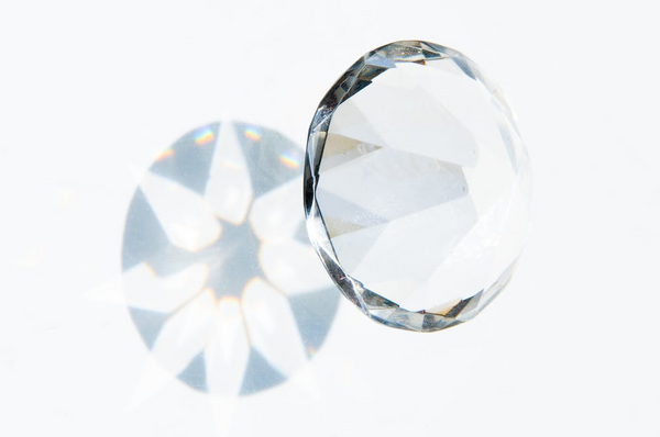 a diamond and light refracting from it onto a white background