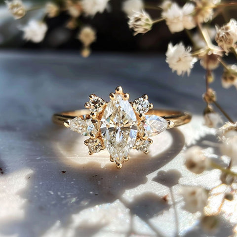 Fairycore style fantasy engagement ring with celestial cluster of diamonds and a center cut marquise diamond