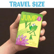 Child's hand holding the Jump 1 game with a dark brown background. Text  on the top of the image says "travel size".