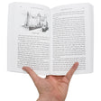 A hand holding open The Story of the World, Volume 2, The Middle Ages to show inside pages. The left page has a black and white illustration at the top of a stone castle with text underneath. The right page is covered in text.