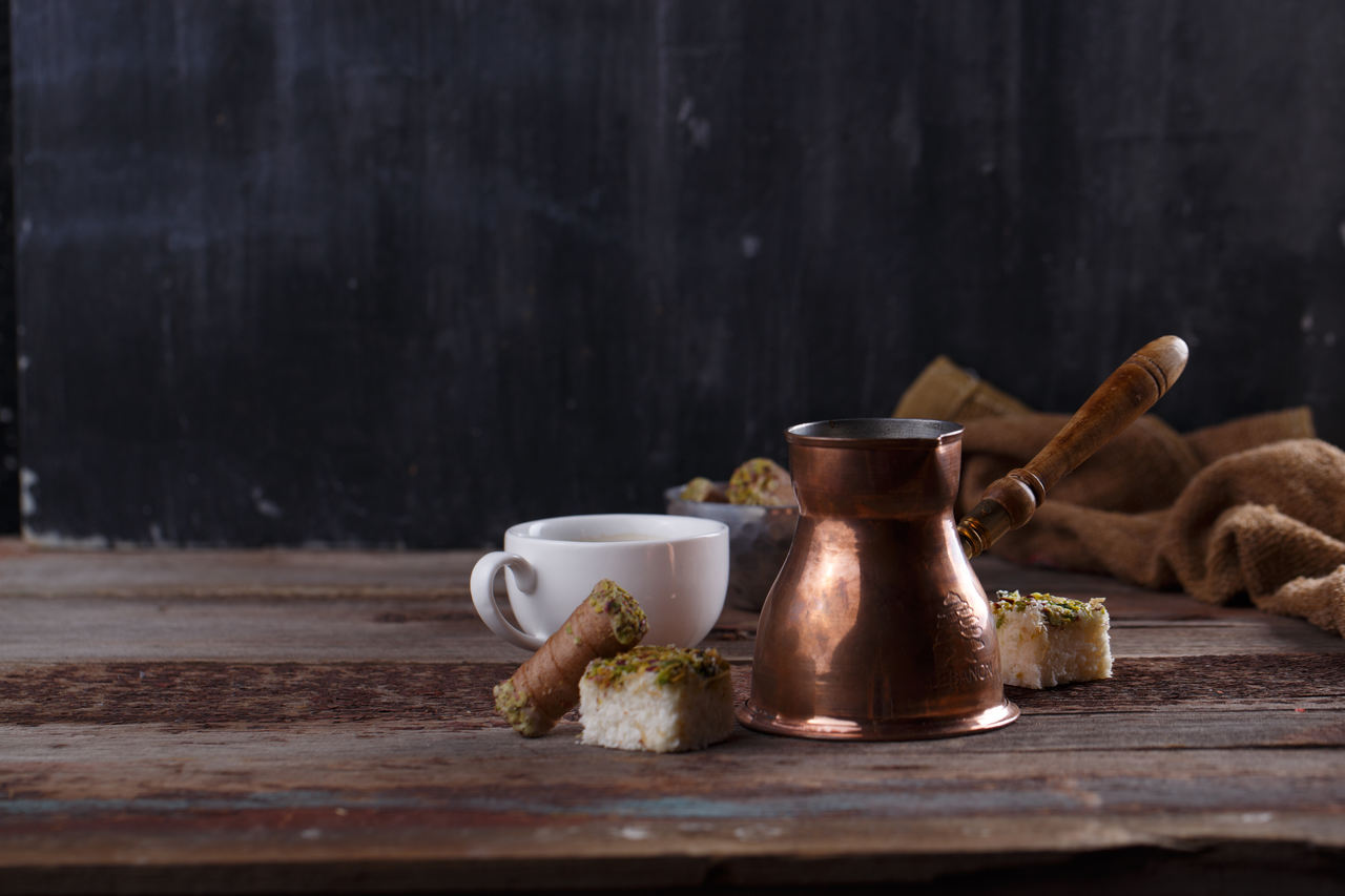 masanın üzerindeki bir fincan Türk kahvesi ve bakır cezve