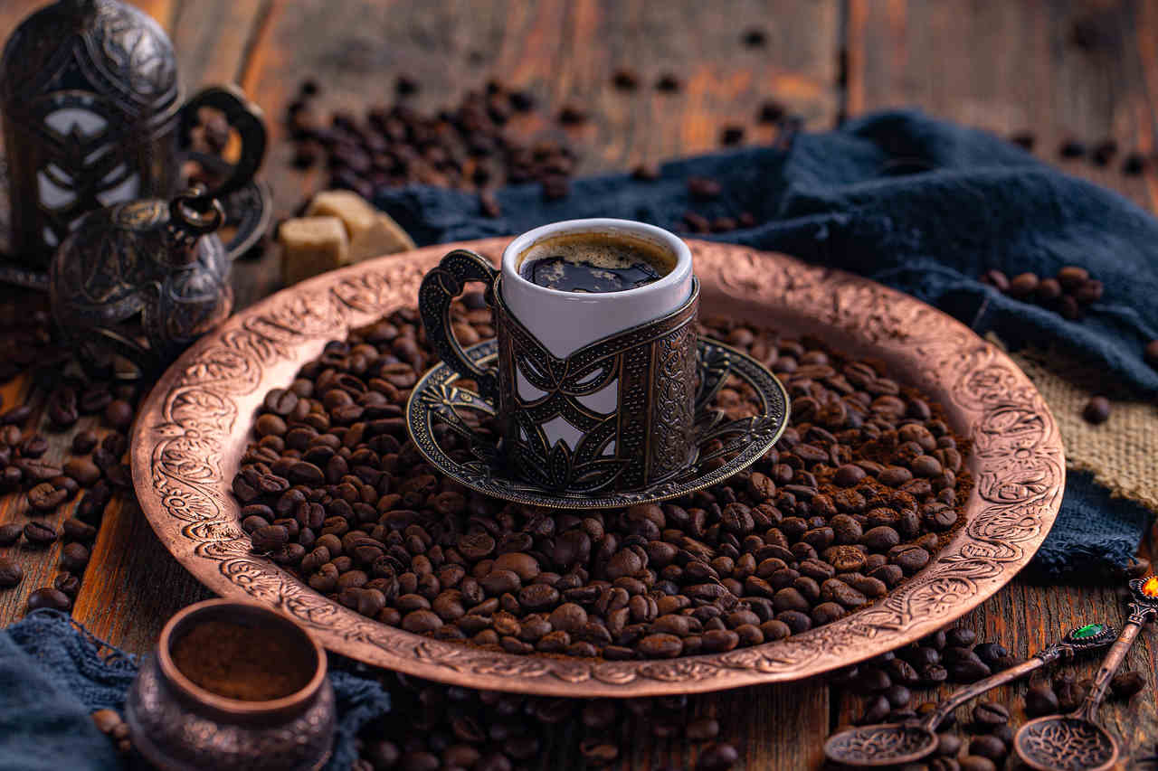 bakır tepsideki kahve çekirdeklerinin üzerinde duran Türk kahvesi fincanı