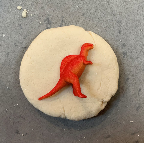 Salt dough circle with orange dinosaur toy