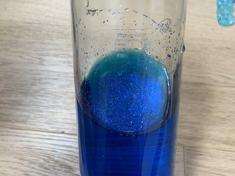 Glass bottle half full with blue water and glitter