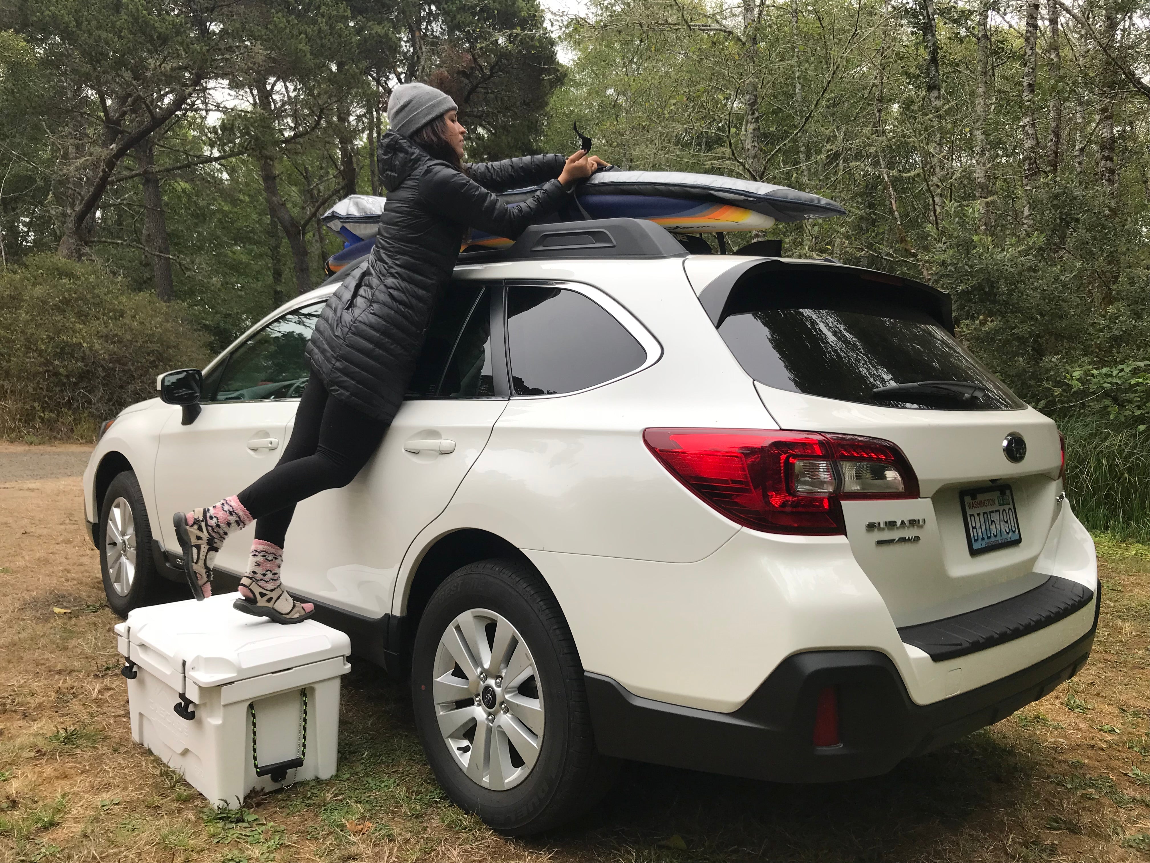 standing on a camping cooler to load up the car