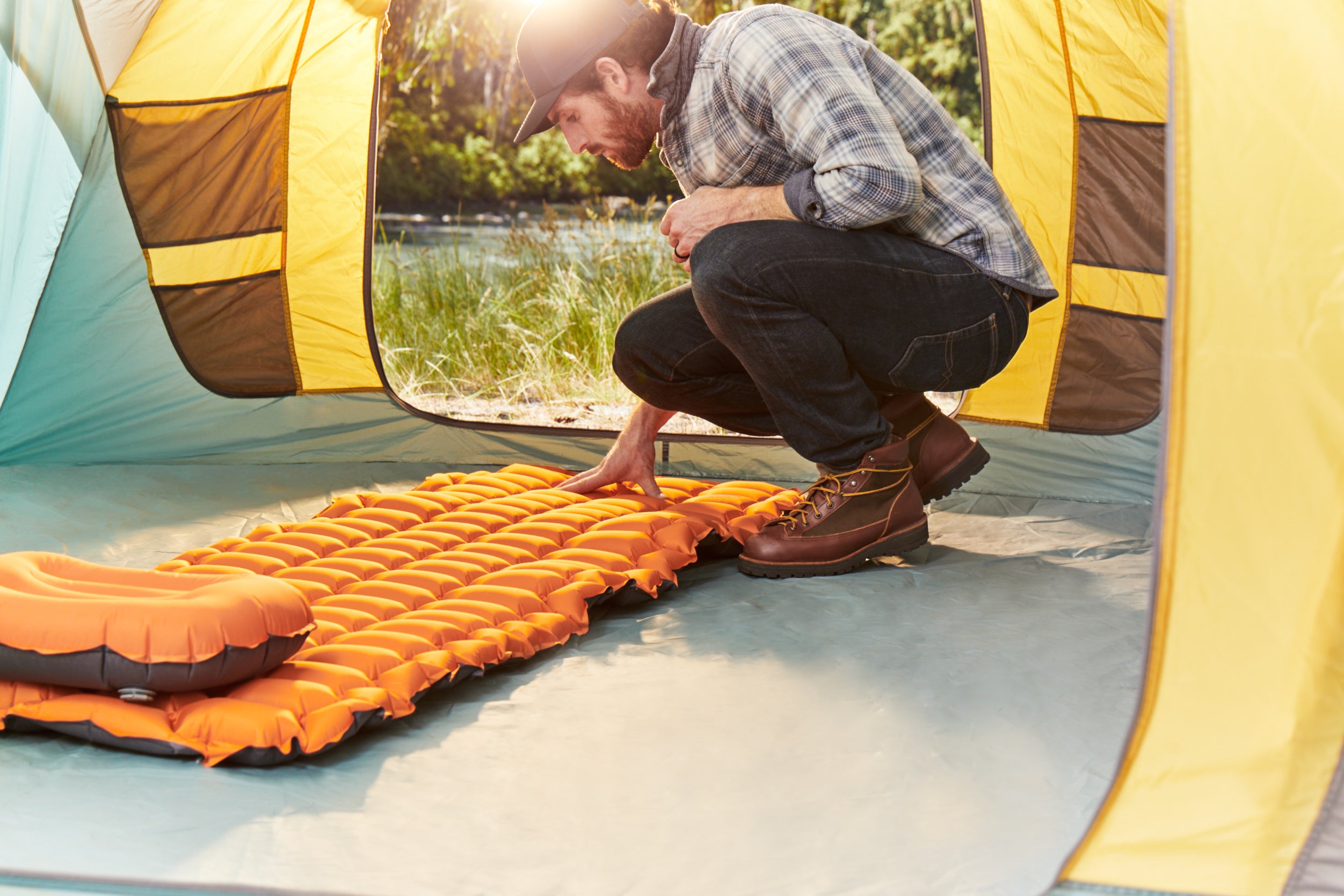 Person folding orange sleeping pad