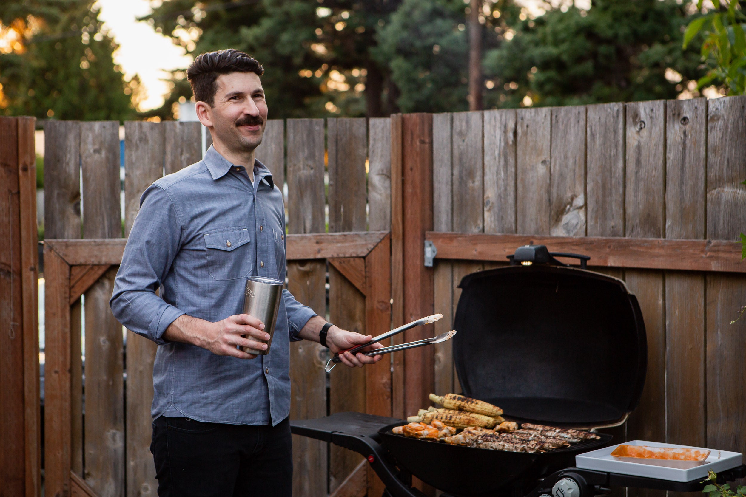 man barbecues his favorite camping recipe in the back yard