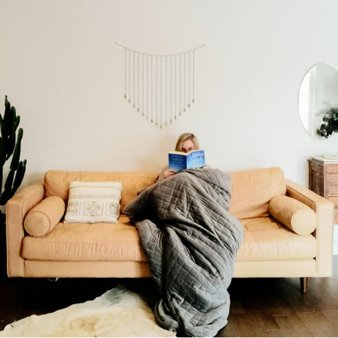 a lady sitting on the couch with her weighted blanket