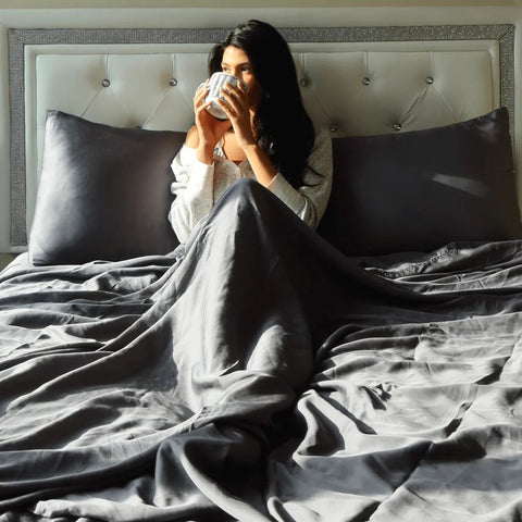a lady enjoying coffee in bed under a weighted blanket