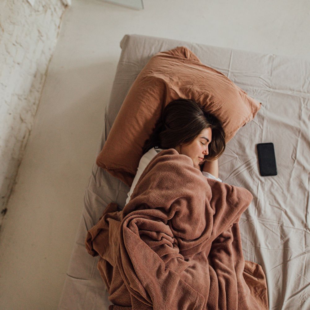 Woman fast asleep, phone resting beside her