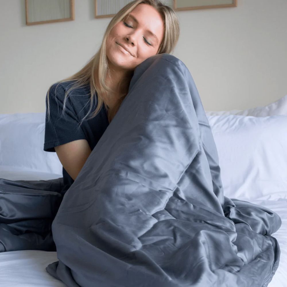 Woman sitting in bed enjoying her weighted blanket