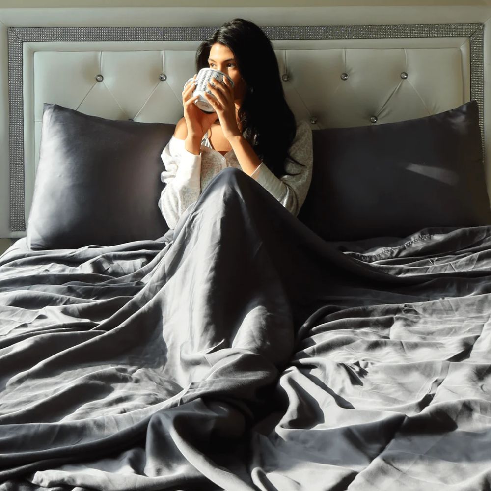 Woman drinking coffee in bed with her weighted blanket