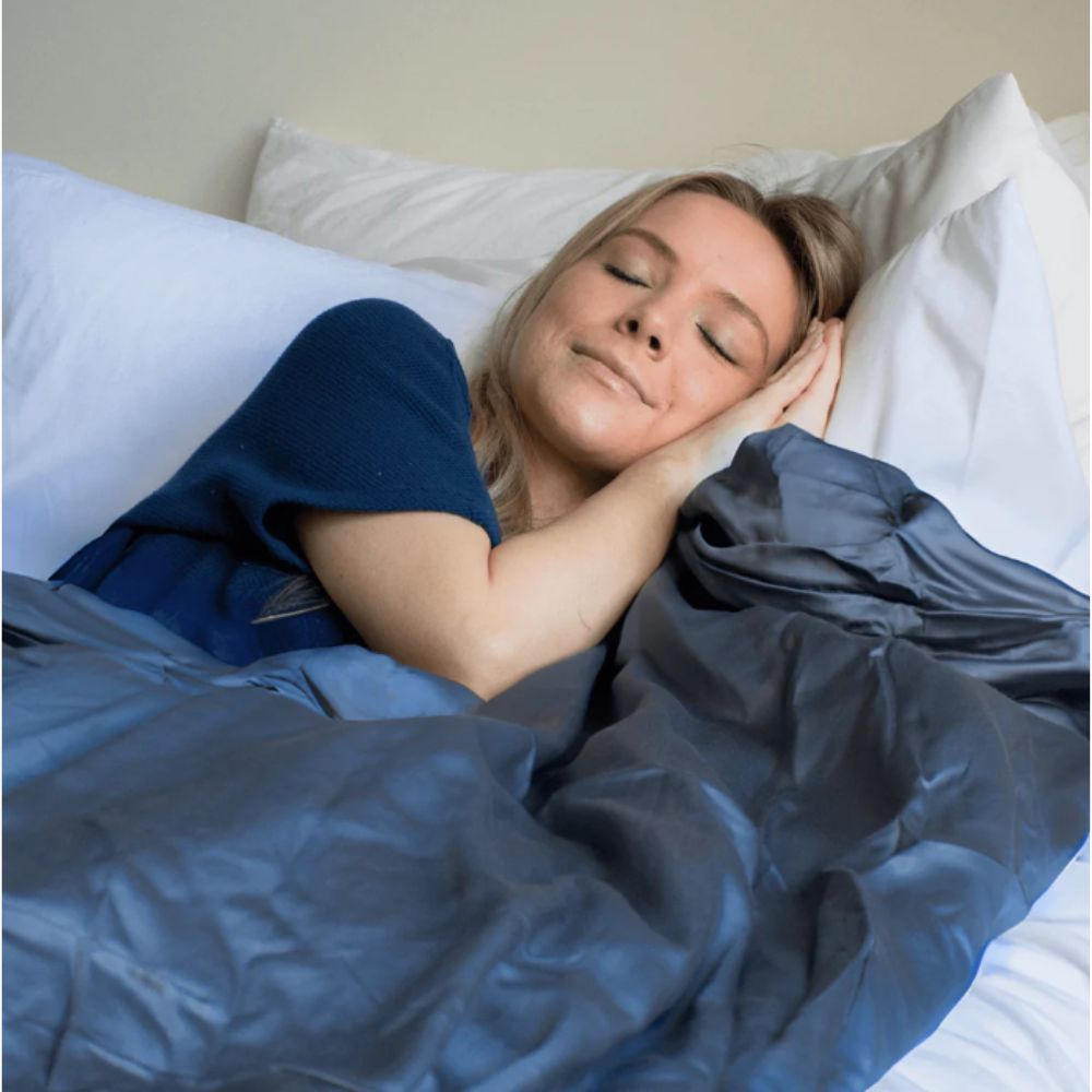 Woman sleeping soundly in bed, covered with a Gravid cooling weighted blanket