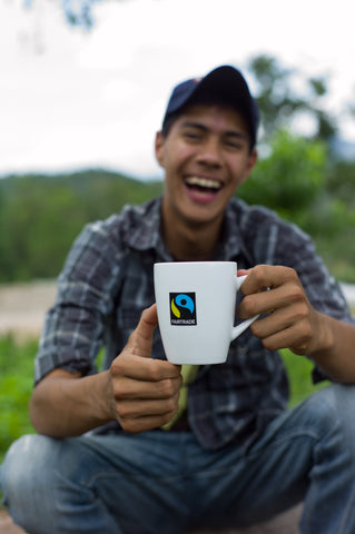Fairtrade logo on coffee cup with Fairtrade farmer holding and smiling