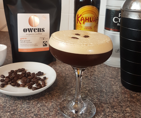 Espresso Martini Cocktail in a glass with vodka bottle, Owens Coffee, Kahula, coffee beans and cocktail shaker in background