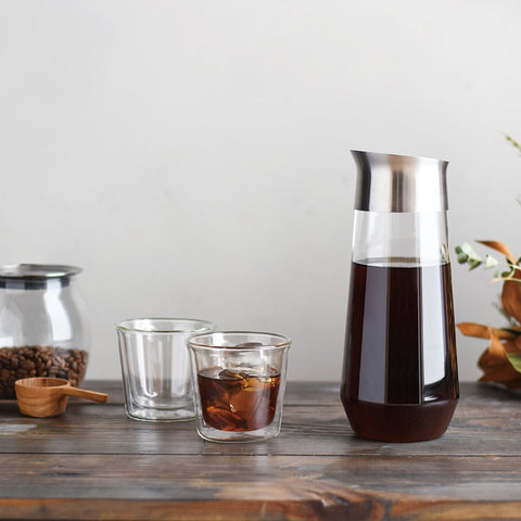 Kinto Luce Cold Brew carafe with cold brew in it on a table with coffee cups