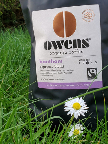 Bag of Owens organic coffee beans from UK in grass with daisies