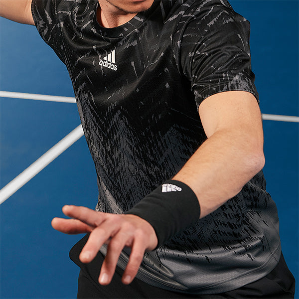 Action shot of man playing tennis in adidas tennis clothing