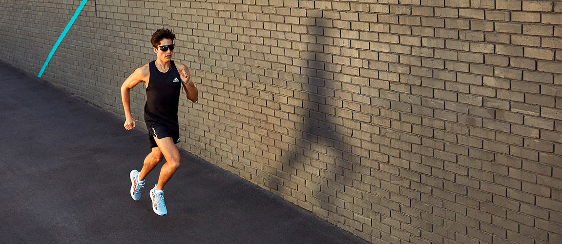 Action shot of man running in men's adidas running shoes on concrete